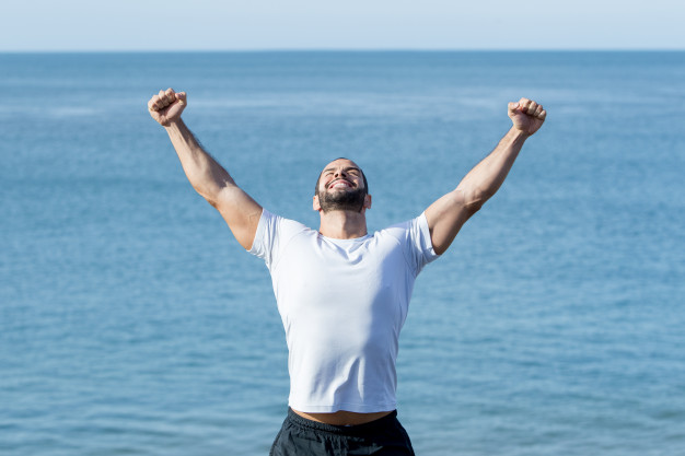 Счастливый сильный человек, отмечающий спортивный успех на море | Бесплатно Фото